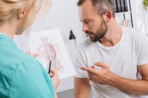 chiropractic showing human body picture to male patient during appointment in clinic